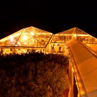 40' x 60' and 40' x 40' clear top tents at night with chandeliers.