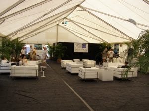Inside view of a 40' x 100' frame tent with gable ends, window sidewalls, black carpet, and white leather furniture used at the 2010 Stuart boat show.