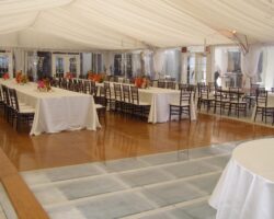 Wedding at a hotel featuring a combination wood and acrylic pool cover, 40' x 100' frame tent, tent liner, leg drapes, and clear sides.