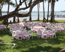 Wedding at a private waterfront home featuring white wood chairs and pink poly linens.