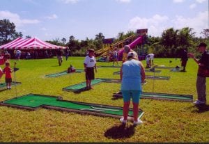 Miniature golf game at corporate picnic for 1,800 with cargo slide in the background.
