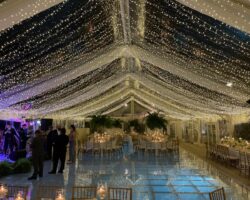 Wedding in a 40’ x 90’ clear tent featuring fairy lights and a clear acrylic pool cover.